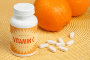 bottle of vitamin C supplement and orange fruits