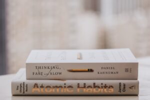 Two books sitting on a desk, one is titled "Atomic Habits"